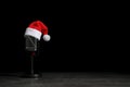 Microphone with Santa hat on grey stone table against black background. Christmas music Royalty Free Stock Photo