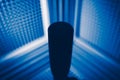 Microphone silhouette in sound recording studio, blue acoustic foam background