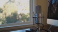 A microphone is sitting on a desk in front of a window Royalty Free Stock Photo