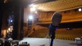 Microphone on the stage and empty hall during the rehearsal. Microphone on stage with stage-lights in the background