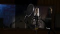 Microphone on a stand located in a music studio recording booth under low key light