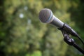 Microphone on a stand at an open-air event against a green nature background, symbol for festival, entertainment, music or party, Royalty Free Stock Photo