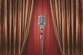 Microphone stand before shiny orange curtains, theatrical setting Royalty Free Stock Photo