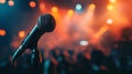 A microphone stands on a stage surrounded by a blurry crowd and bright lights. Royalty Free Stock Photo