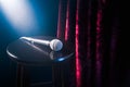 Microphone on a wooden stool on a stand up comedy stage with reflectors ray, high contrast image Royalty Free Stock Photo