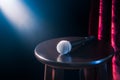 Microphone on a wooden stool on a stand up comedy stage with reflectors ray, high contrast image Royalty Free Stock Photo