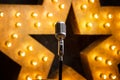 Microphone on theater or karaoke stage, golden luminous star on background Royalty Free Stock Photo