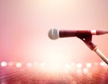 Microphone on vibrant lighting concert, wooden floor background