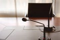 Microphone on a wooden table and an empty chair in a boardroom