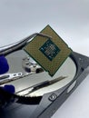 Microprocessor CPU chip on pincer against a silver hard disk plate closeup view Royalty Free Stock Photo