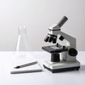 Microscope with Beaker and Notebook on White Desk Royalty Free Stock Photo