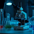 A microscope is illuminated under blue lighting in a laboratory setting. Surrounding it Royalty Free Stock Photo