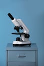 Microscope on laboratory cabinet against blue background Royalty Free Stock Photo