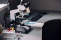 Microscope, rack with test tubes and vials on table in laboratory Royalty Free Stock Photo