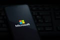 Microsoft logo on smartphone screen laying on computer keyboard