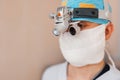 Microsurgeon man in a white mask in special medical clothes and glasses with binocular loupes in the operating room. surgeon makes