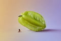 Microworld with woman figure under the carambola tropical fruit on green pink background. Cartoon style, food photography.