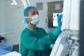 Mid adult African American woman adjusting medical monitor controls in operating room, copy space