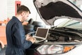 Worker Using Laptop To Detect Malfunction In Car At Garage