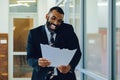 Mid adult bearded black man Entrepreneur Businessman wearing suit holding papers and talking on smartphone laughing