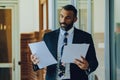 Mid adult bearded black man Entrepreneur Businessman wearing suit holding papers walking in office