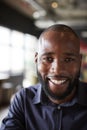 Mid adult black male creative sitting in an office social area, head and shoulders close up, vertical, crop