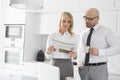 Mid adult business couple reading newspaper while having coffee in kitchen