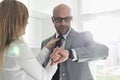 Mid adult businessman checking wristwatch while woman adjusting his tie at home