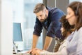 Mid adult businessman using laptop with colleagues wearing headsets in office Royalty Free Stock Photo