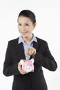Mid adult businesswoman saving money in piggybank. Conceptual image