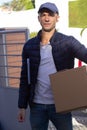 Mid adult deliveryman carrying cardboard box