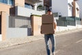 Mid adult deliveryman carrying stack of boxes