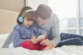 Mid adult father with boy listening music on headphones in bedroom Royalty Free Stock Photo