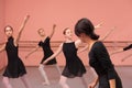 Mid adult female ballet teacher instructing medium group of teenage girls