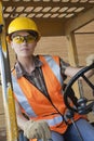 Mid adult female industrial worker driving forklift truck