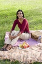 Mid-adult Indian woman sitting on picnic blanket