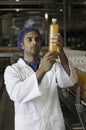 Mid adult industrial worker examining bottle in factory