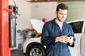Maintenance Worker Using Mobile Phone In Auto Repair Shop