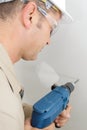 mid-adult male builder drilling hole in wall Royalty Free Stock Photo