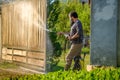 Mid adult man cleaning a wooden gate with a power washer. High pressure water cleaner used to DIY repair garden gate. Royalty Free Stock Photo