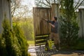 Mid adult man cleaning a wooden gate with a power washer. High water pressure cleaner used to DIY repair garden gate. Royalty Free Stock Photo