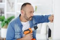 mid-adult man drilling hole in wall