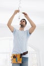 Mid-adult man fixing light bulb wiring in new house