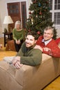 Mid-adult man and senior parents by Christmas tree