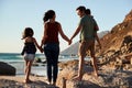 Mid adult parents and their two pre-teen children standing on beach admiring the view, full length