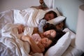 Mid adult parents and their two young children lying asleep in bed, waist up, close up Royalty Free Stock Photo