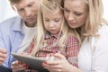 Mid adult parents using tablet PC with daughter at home