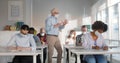 Mid adult professor wearing face mask while talking to a group of college students in lecture room Royalty Free Stock Photo