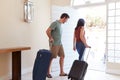 Mid adult white couple at their front door leaving home with luggage to go on vacation, full length Royalty Free Stock Photo