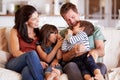 Mid adult white couple and their two young children sitting on a sofa at home smiling at each other Royalty Free Stock Photo